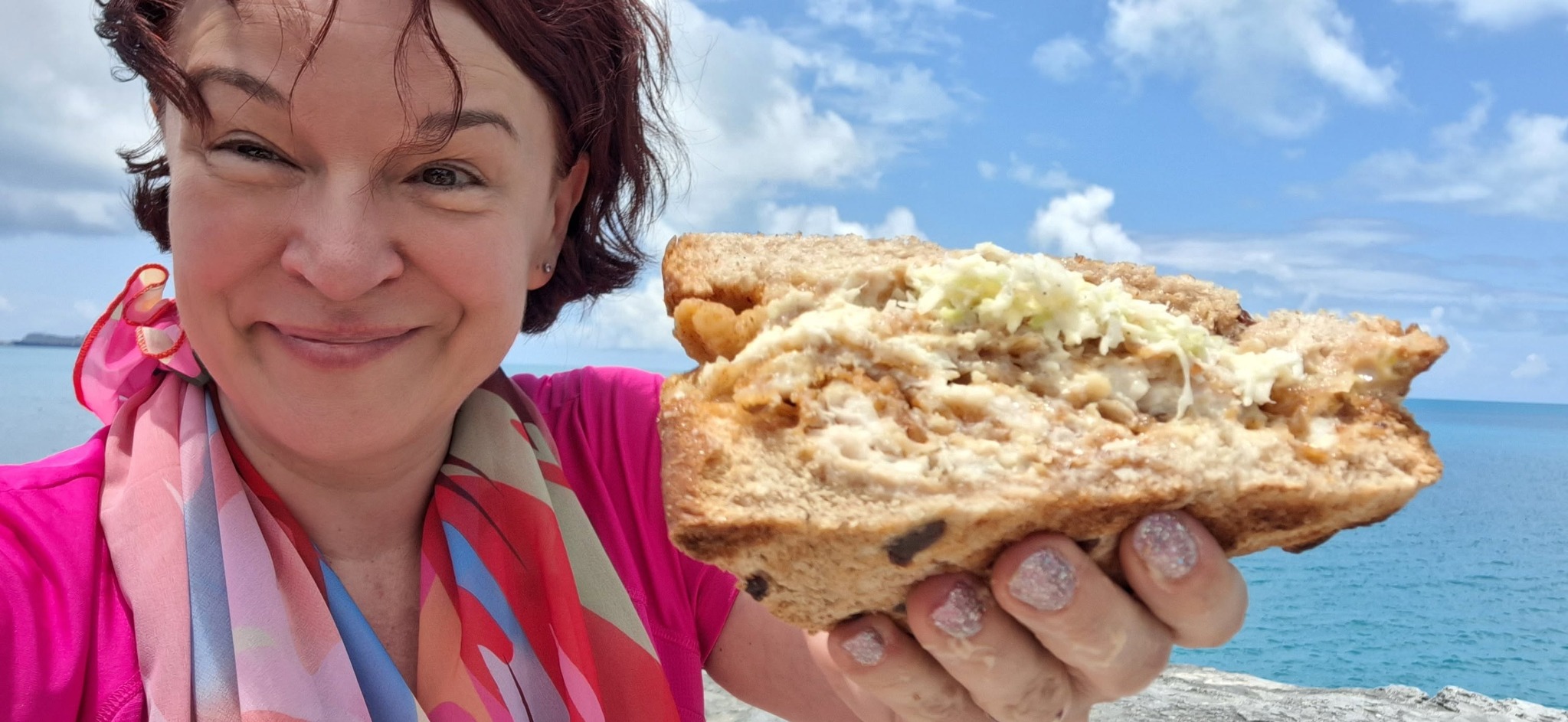 Edina enjoying Bermuda's famous fish sandwich beside the blue water